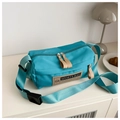 Detail of lake blue nylon cylinder crossbody bag with leather patch on a minimal cabinet - 6152 / Blue