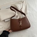 Bolso hobo de cuero marrón con cierre de pistón dorado sobre un elegante blazer beige - Marrón