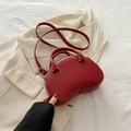 Dunkelrote Halbmond-Bowlingtasche aus Leder mit verstellbarem Riemen auf beigem Blazer - Rot