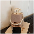 Detail of woven bucket bag featuring elegant pearl handle and gold chain shoulder strap - Khaki