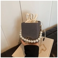 Close-up of woven bucket bag with large pearl handle and drawstring inner pouch - Black