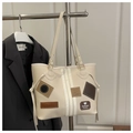 Detail of beige tote bag featuring fashionable decorative patches and contrast piping - White