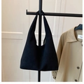Détail d'un sac hobo noir mat suspendu à un support à côté d'un trench-coat classique - Noir