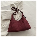 Detail view of burgundy faux suede hobo bag with adjustable strap on white fabric - Red