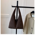 Détail d'un sac cabas en daim marron foncé avec coutures minimalistes dans un décor de studio - Café