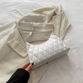 Minimalistische weiße Stepptasche mit goldener Hardware auf beigem Blazer - Weiß