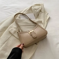 Elegante bolso de hombro beige con hebilla de metal dorado sobre chaqueta crema - Caqui