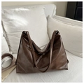 Nahaufnahme der dunkelbraunen Hobo-Tasche aus mattem Kunstleder auf einem weißen Sofa - Braun