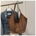 Détail d'un sac cabas en daim marron avec étiquette vintage et texture brossée douce - café