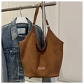 Détail du sac cabas en daim marron foncé avec bandoulière sur fond de veste en jean - Marron