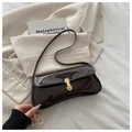 Deep brown patent leather underarm bag with gold clasp on a beige suit background - Coffee