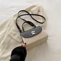 Bolso bandolera de paja con solapa de cuero negro y hebilla plateada sobre chaqueta - Negro