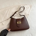 Bolso sobaco vintage de cuero marrón oscuro con hebilla dorada sobre fondo crema - Marrón