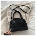 Dettaglio borsa nera con stampa leopardata e fibbie dorate su sfondo di blazer beige - Nero