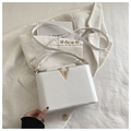 Detalle del cuero granulado blanco y herraje en V dorado en un bolso bandolera - Blanco Roto