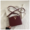 Detalle de bolso burdeos en piel granulada con logo V dorado y correa fina ajustable - Rojo