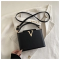 Detalle de bolso en cuero granulado negro con hebilla metálica dorada en forma de V - Negro