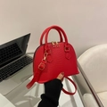 Macro shot of red snake-pattern shell bag featuring gold hardware and double zippers - Red