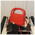 Detail of red crossbody bag with curved flap and Fashion text on a black chair - Red