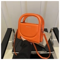 Detail der leuchtend orangefarbenen Handtasche mit Rundgriff und Mode-Schriftzug - Orange