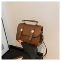Gros plan d'un petit sac rétro marron avec boucles métalliques doubles et poignée sur le dessus - Marron