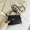 Bolso de mano chic en cuero negro con hebilla cuadrada y correa sobre blazer beige - Negro