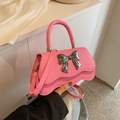 Pink crossbody bag with silver bow accent and wave-edge design on white background - Pink
