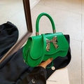 Chic green leather handbag with a large silver metal bow and wavy bottom detail - Green