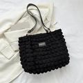 Black bubble texture shoulder bag with fashion label on white blazer background - Black