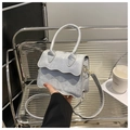Detalle del bolso metalizado plateado con solapa ondulada y asa cilíndrica - Gris