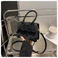 Detalle de mini bolso de terciopelo negro con solapa ondulada y herrajes dorados - Negro