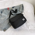 Minimalist black canvas messenger bag with adjustable shoulder strap and woven label - Black