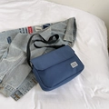 Minimalist navy blue canvas messenger bag with adjustable strap on denim backdrop - Blue