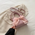 Pink crossbody bag with large mesh bow accent on white blazer background - Pink