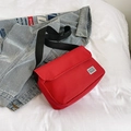 Minimalist red canvas messenger bag with black nylon strap and woven brand label - Red