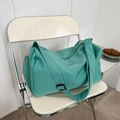 Grande borsa da viaggio in nylon verde menta con tracolla su sedia in una caffetteria - verde scuro