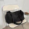 Grande borsa da viaggio in nylon nero con ampia tracolla su sedia pieghevole color crema - Nero