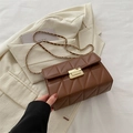 Chic brown quilted crossbody bag with gold buckle and chain strap on beige blazer - Brown