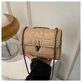 Detailansicht der beigefarbenen Stepptasche mit Metallverschluss und Kettenriemen in der Hand - Khaki