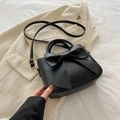 Elegante schwarze Handtasche mit Schleife und Gold-Hardware auf beigem Blazer - Schwarz