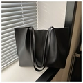 Close-up of a minimalist black leather tote bag featuring vertical double stitching details - Black