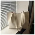 Detailed texture of minimalist off-white tote bag with smooth matte finish on a windowsill - White