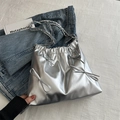 Silberne Metallic-Beuteltasche mit Schleifen und Kettenriemen auf Jeans-Hintergrund - Silber
