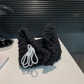 Borsa a mano nera con trama popcorn e dettaglio nodo intrecciato bianco su tavolo bianco - Nero