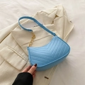 Sky blue quilted underarm bag with gold chain strap on white blazer backdrop - Lake Blue