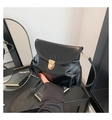 Detalle de un bolso negro de cuero mate con hebilla dorada y costuras finas de precisión - Negro