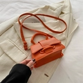 Mini sac bandoulière orange vif avec texture litchi et boucle dorée sur costume beige - Orange