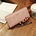 Pink faux leather long wallet with zipper and wristlet shown in a warm lifestyle setting - Pink