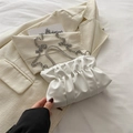 White pleated cloud bag with crystal handle and silver chain on a beige blazer - White