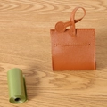 Brown PU leather dog waste bag dispenser with metal ring on wooden background - Brown
